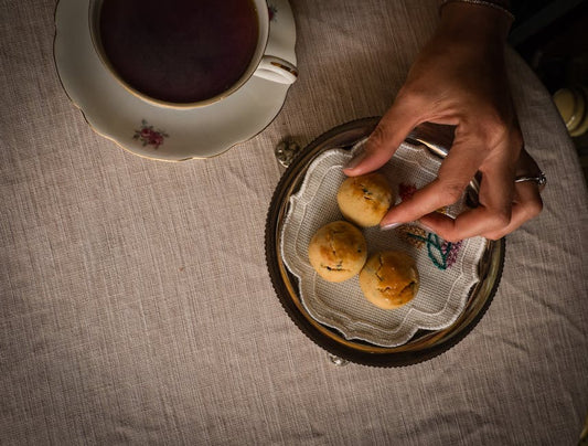 Overhead view of a hand picking cookies beside a cup of tea. Perfect for tea break and snack themes.